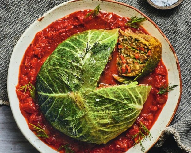 A whole stuffed cabbage on a bed of tomato sauce