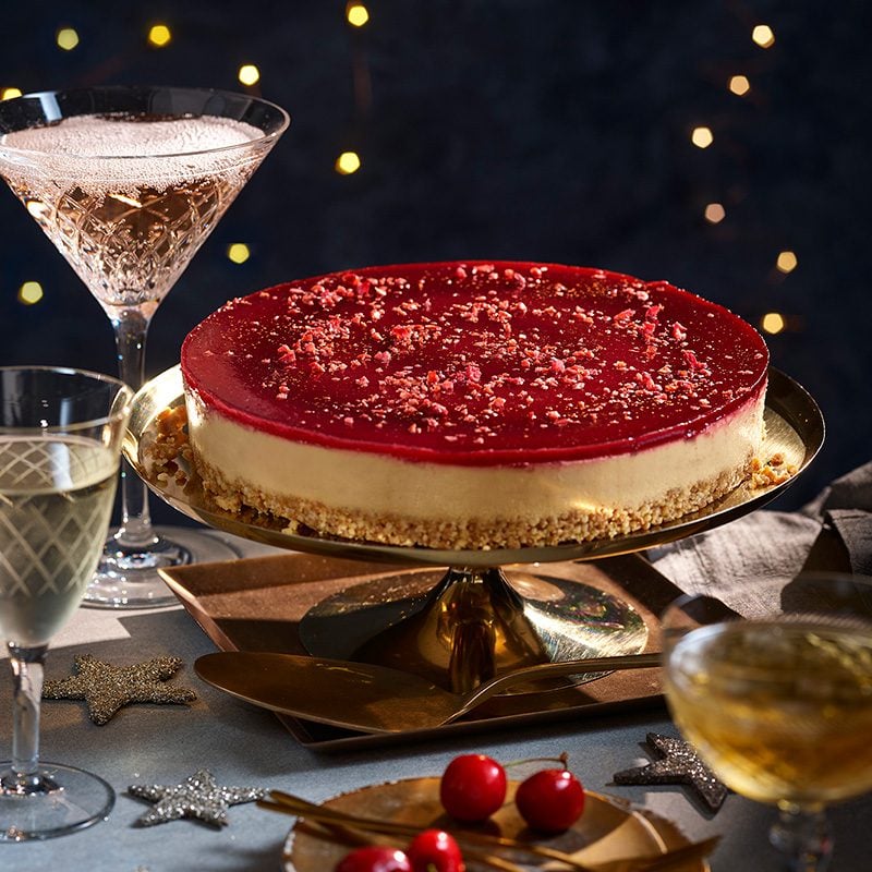 A cherry cheesecake on a gold cake stand