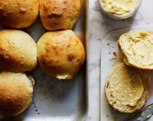Golden bread rolls on a tray with a pot of butter