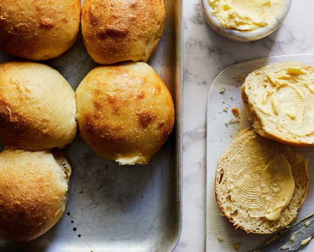 Golden bread rolls on a tray with a pot of butter
