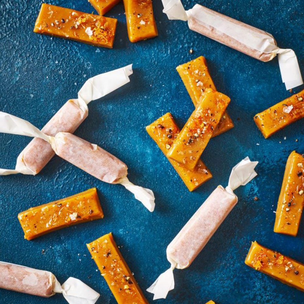 Batons of salted caramel scattered on a blue surface, for Christmas hamper ideas