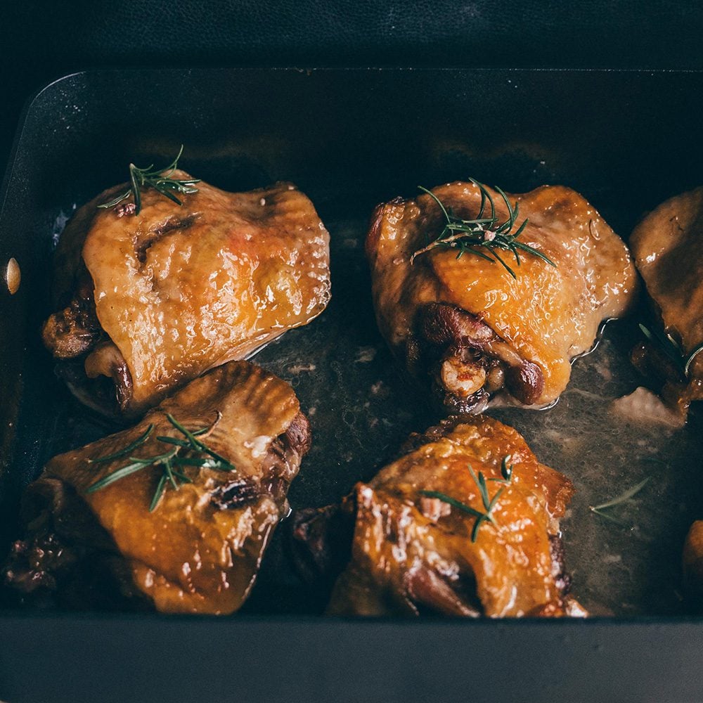 Four roasted turkey thighs in a roasting tray