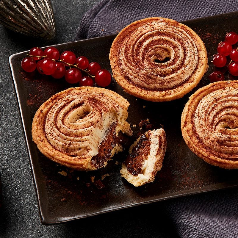 Three individual pastry tarts topped with icing, with one cut open