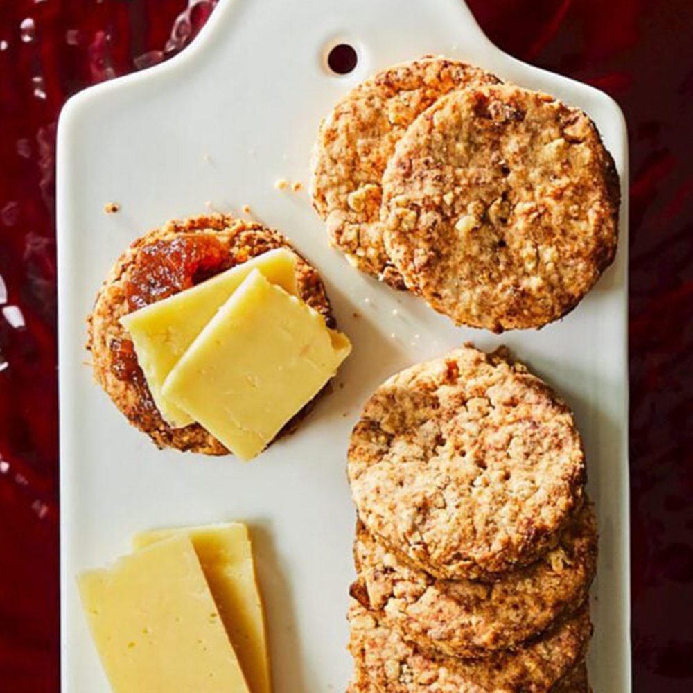 Circular biscuits on a platter with slices of cheese, for Christmas hamper ideas