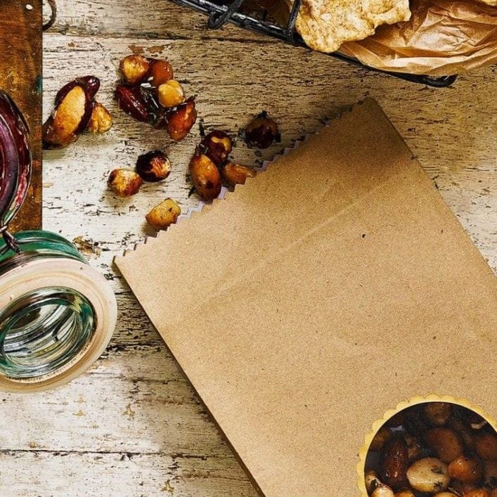Honey roast nuts tumbling out of a brown paper bag, for Christmas hamper ideas