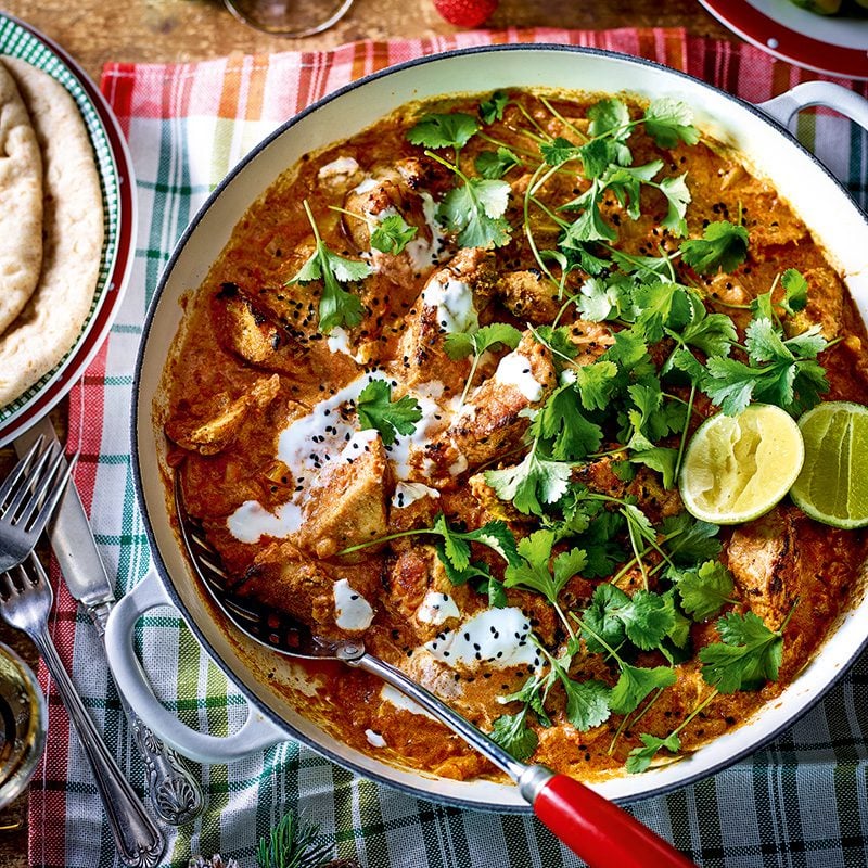 A casserole dish of turkey curry, topped with herbs