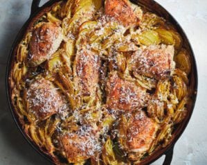 A circular roasting pan filled with golden dauphinoise potatoes and chicken gratin