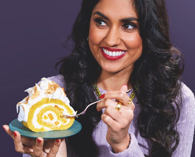 Portrait of pastry chef Ravneet Gill, holding a plate with a slice of roulade