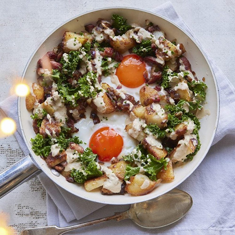Potato hash in a frying an with kale and fried eggs