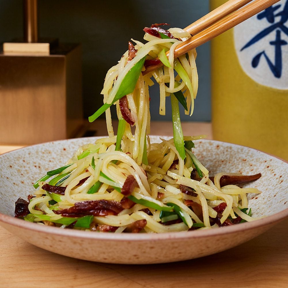 Stir-fried potato slivers with wind-dried bacon in a dish