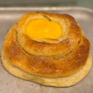 A golden bun filled with a pool of yellow vanilla custard