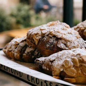 A box of bronze almond croissants, dusted in powdered sugar