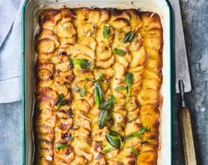 A tray of golden brown pommes anna, thinly sliced potatoes, topped with sage leaves
