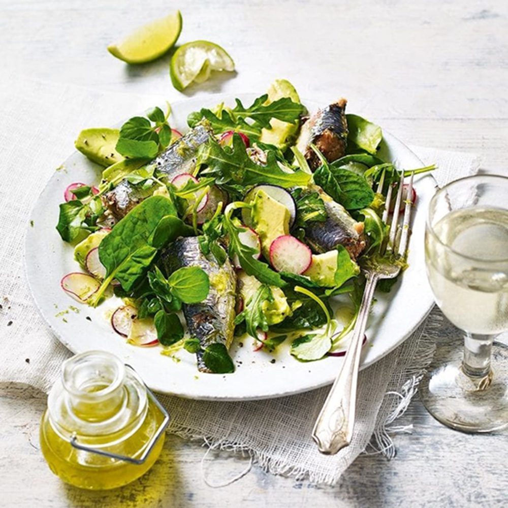 A plate of salad including tinned sardines, with olive oil on the side