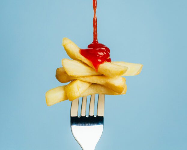 A fork spearing chips, with ketchup drizzling