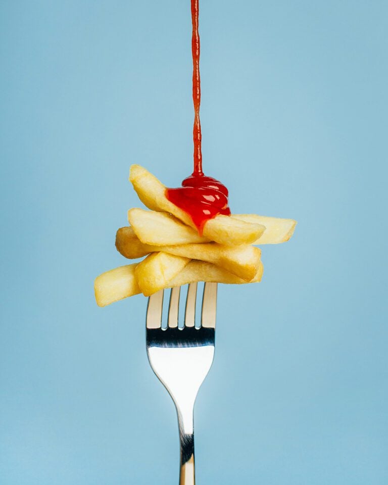 A fork spearing chips, with ketchup drizzling