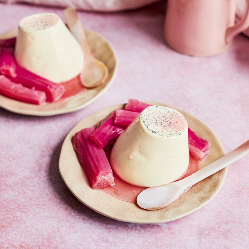 Two plates with a pannacotta on each, with pink poached rhubarb on the side