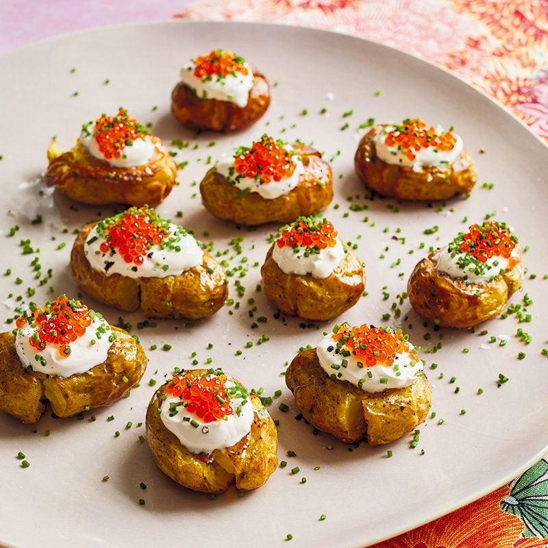 A platter of potatoes topped with crème fraîche and roe, sprinkled with chives