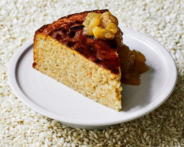 A slice of brûléed rice pudding cake with pear compote on a white plate